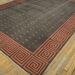 Dark flatwoven rug with rust key border and scattered geometric motifs on worn wood floors.
