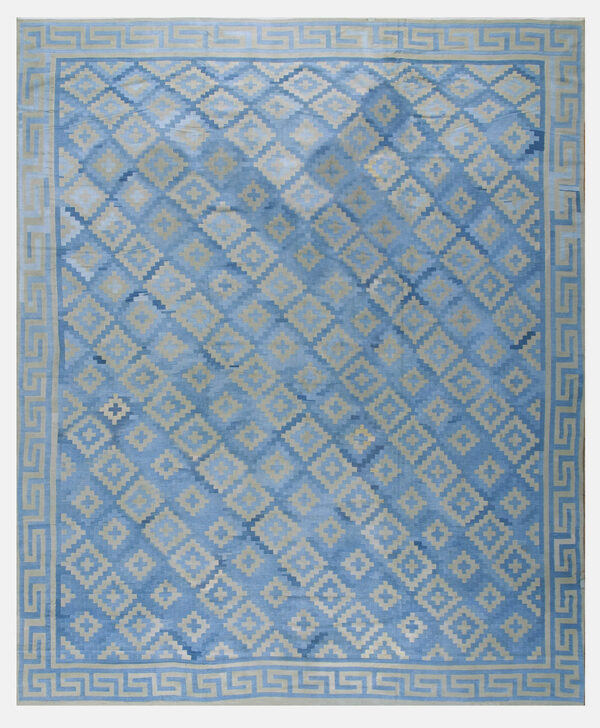 Blue rug with light tan geometric diamonds, prominent color variation, and a greek key patterned border.