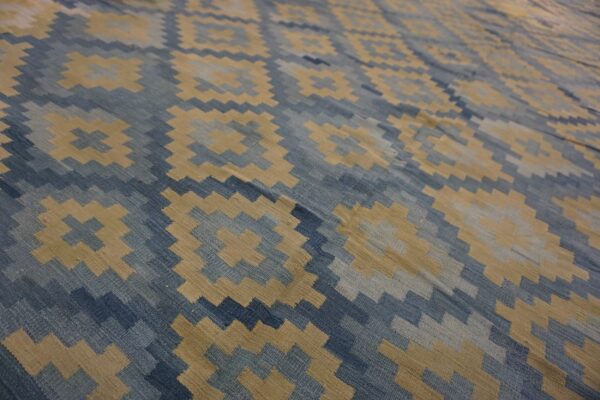 Flatweave rug featuring a stepped diamond and cross geometric pattern in shades of blue and tan.