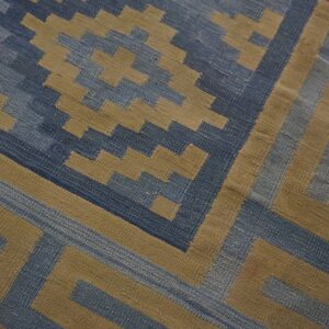 Blue and tan flatweave rug featuring a geometric pattern of stepped diamonds and angular borders.