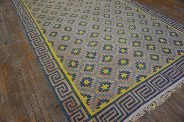 Geometric blue and yellow diamond pattern rug with a greek key border displayed on rustic wood floors.