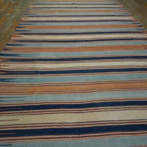 A runner featuring horizontal stripes of indigo, teal, terracotta, and cream rests on wooden flooring.