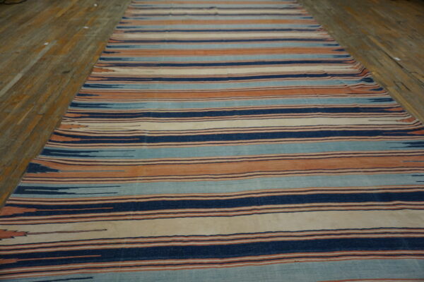 A runner featuring horizontal stripes of indigo, teal, terracotta, and cream rests on wooden flooring.