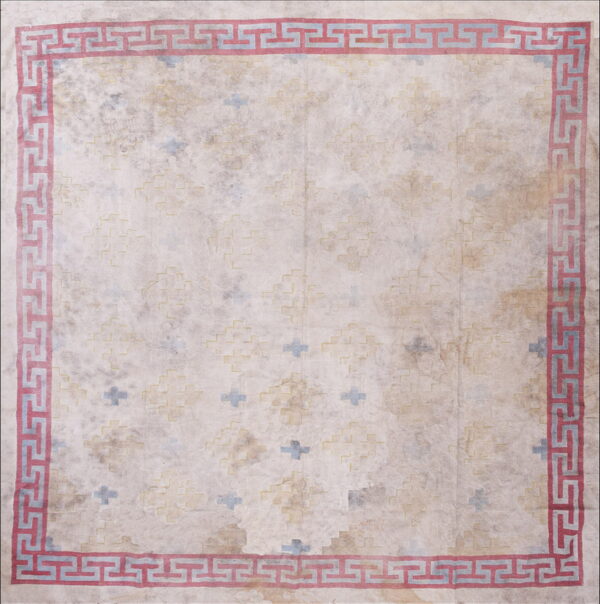 Distressed cream rug with a geometric faded yellow and blue field pattern and a bold red greek key border.
