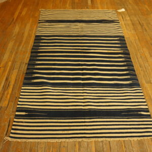 Navy and cream striped runner rug with short fringe rests on rustic wood planks.