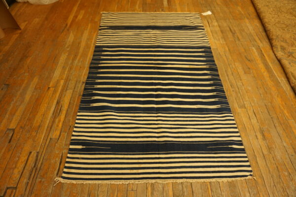 Navy and cream striped runner rug with short fringe rests on rustic wood planks.