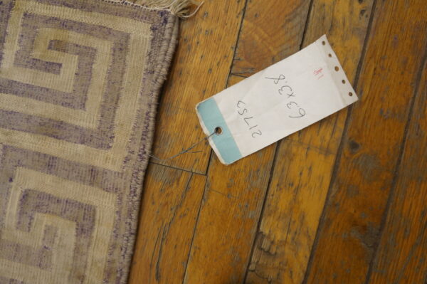 Antique dhurrie small scatter size cotton brown rug 7 Beige and faded purple flatweave rug with a stepped geometric pattern sits on wood flooring near a tag.