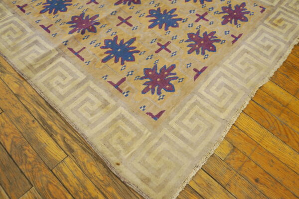Antique dhurrie small scatter size cotton brown rug 5 A flatwoven rug with a gold field, blue and purple stars, and a light greek key border rests on wood floors.