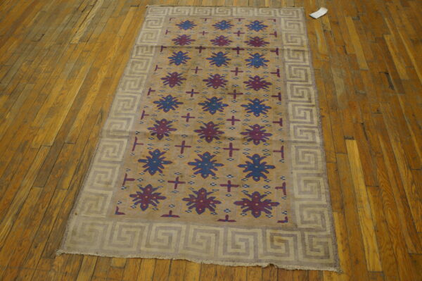 Antique dhurrie small scatter size cotton brown rug 3 Tan rug with alternating blue and burgundy star patterns and a greek key border on a hardwood floor.