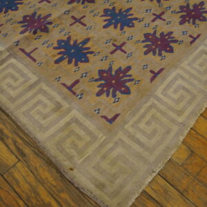Gold and beige geometric rug featuring blue and purple designs rests on rustic wooden planks.