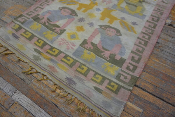 Muted pink, blue, yellow, and green flatweave rug with figures on distressed wood planks.