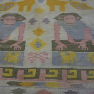 Low-pile rug displaying mirrored human figures and geometric motifs in pink, pale blue, yellow, and olive green.
