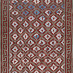 Geometric rug with repeating stepped diamonds in rust, taupe, white, and blue, bordered by a Greek key design.