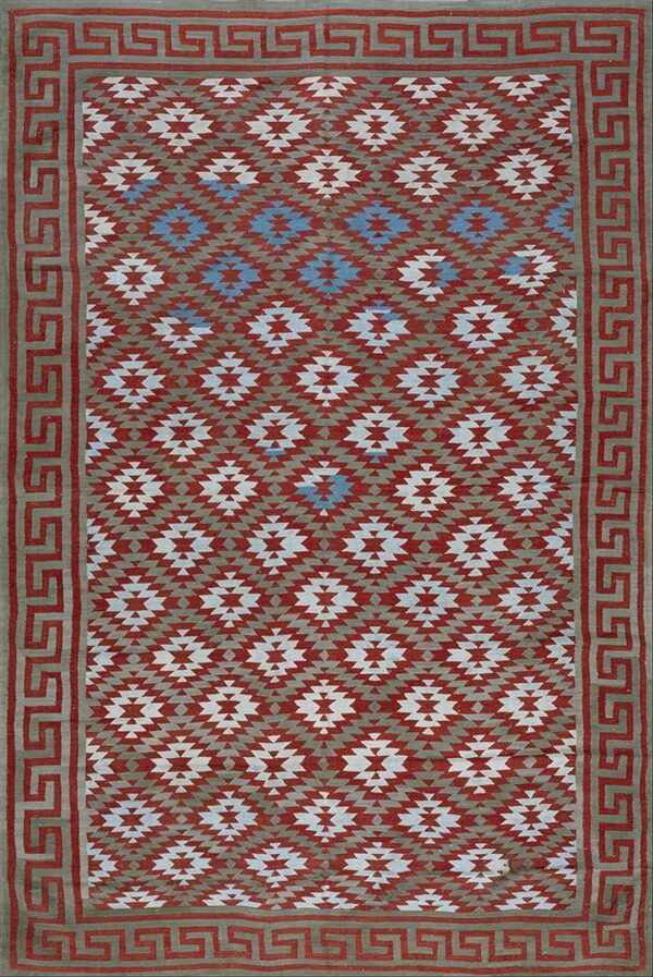 Geometric rug with repeating stepped diamonds in rust, taupe, white, and blue, bordered by a greek key design.