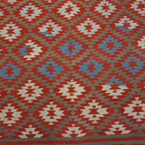 Flatweave rug featuring stepped geometric medallions in red, gray, off-white, and bright blue colors.