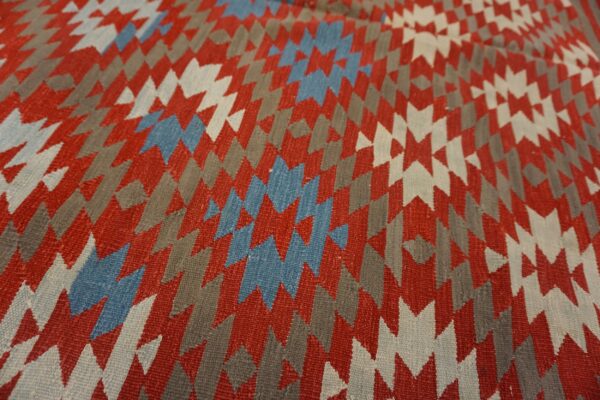 Close-up of a flatweave rug with jagged geometric designs in red, gray, blue, and white.