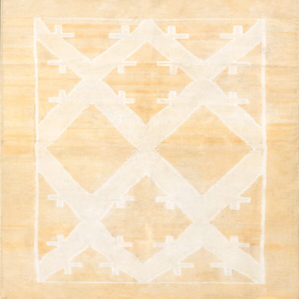 Pale beige rug featuring a prominent white geometric pattern of stepped diamonds and repeating cross shapes.