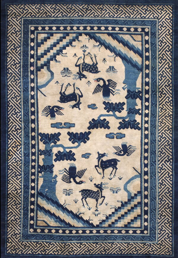 Beige rug with deep blue stylized animals and trees, featuring multiple borders including geometric key patterns.