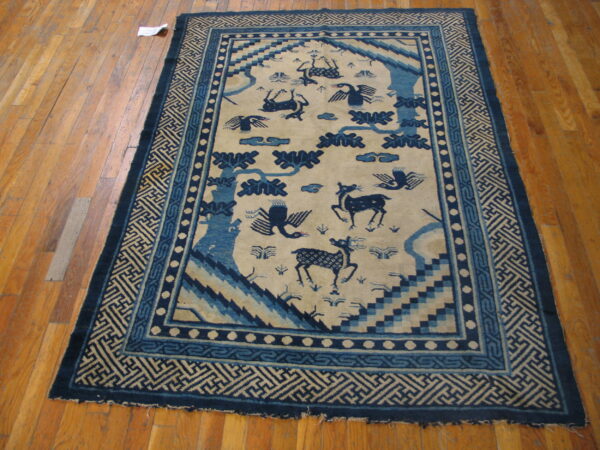 Navy and beige rug with animal motifs and geometric borders lies on glossy hardwood flooring.
