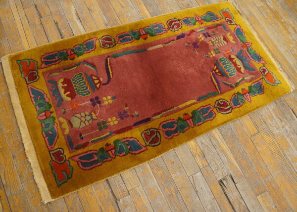 A colorful rug featuring a red field and yellow border rests on rustic wooden floorboards.
