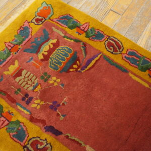 High-pile rug in dusty red with a yellow border featuring multicolored floral patterns on wood flooring.