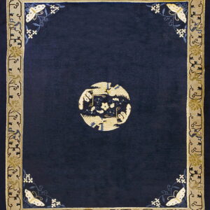 Navy rug with a central gold bird medallion and a detailed beige border with floral and butterfly motifs.