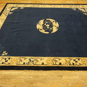 Navy rug with beige borders and a central circular bird design rests on wide-plank wood flooring.