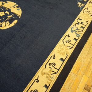 Navy blue rug featuring a vibrant yellow stylized medallion and border on worn hardwood floors.