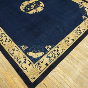 Dark blue rug with a tan border featuring stylized elephants and butterflies rests on light hardwood planks.