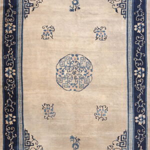 Beige field rug with scattered blue florals and a central medallion, framed by dark blue patterned borders.