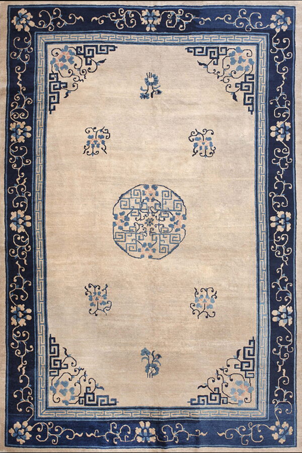Beige field rug with scattered blue florals and a central medallion, framed by dark blue patterned borders.