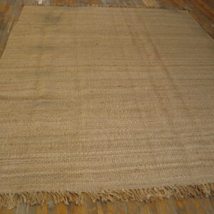Highly textured light brown flatweave rug with fringe on hardwood flooring.