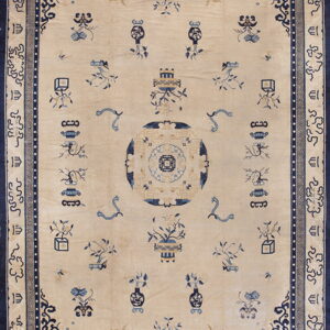 A traditional cream and blue rug featuring a central medallion and scattered vase and plant motifs.