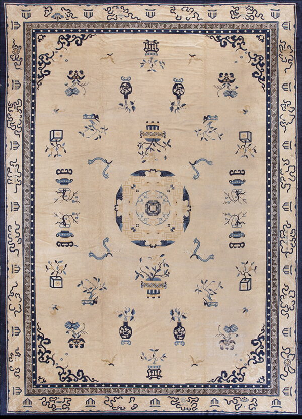 A traditional cream and blue rug featuring a central medallion and scattered vase and plant motifs.