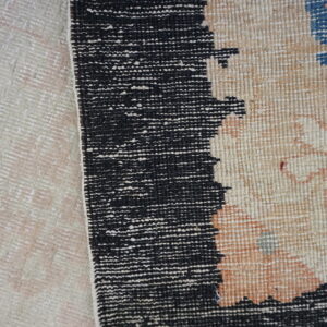 A black speckled border divides a pale woven texture from a patterned beige rug with muted floral accents.