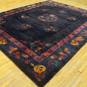 Ornate dark blue rug with large floral medallion and detailed multi-color borders resting on yellow wood flooring.