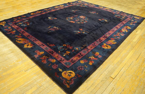 Ornate dark blue rug with large floral medallion and detailed multi-color borders resting on yellow wood flooring.