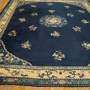Navy blue rug with scattered cream floral motifs and a detailed light-colored border on wood floor.
