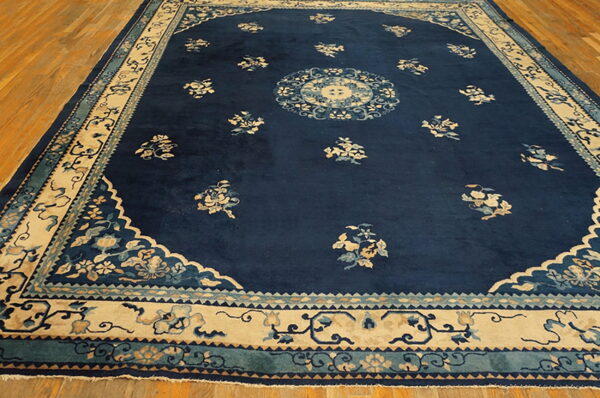 Navy blue rug with scattered cream floral motifs and a detailed light-colored border on wood floor.