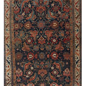 Navy blue area rug featuring an intricate red, pink, and tan floral and stylized animal design.