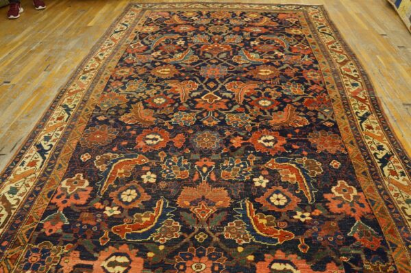 Ornate area rug featuring complex red, rust, and blue stylized floral and animal motifs on dark navy blue ground.
