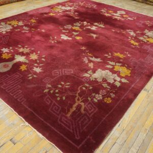 A deep red rug with scattered yellow, green, and cream floral designs on light wood planks.