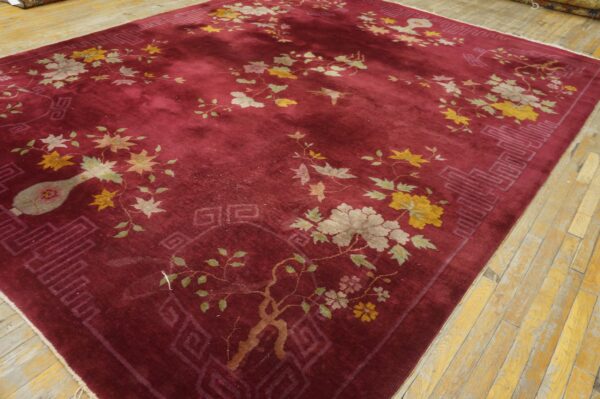 Deep burgundy rug featuring botanical designs in muted yellow, gray, and green on light wood floors.