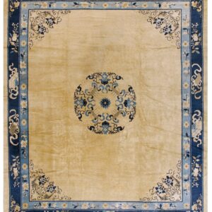 Tan square rug with a navy blue border, light blue accents, and traditional floral patterns.