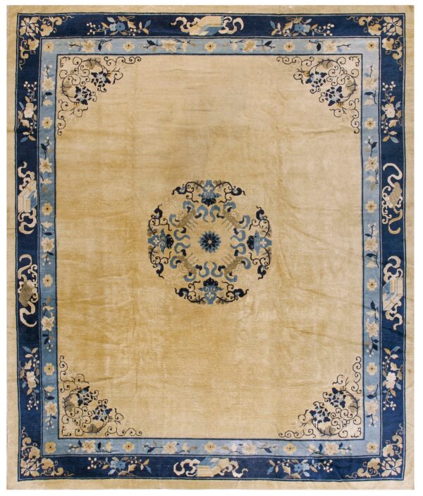 Tan square rug with a navy blue border, light blue accents, and traditional floral patterns.