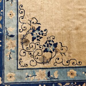 Detailed rug corner showing a beige field and dark blue, light blue, and tan floral borders.