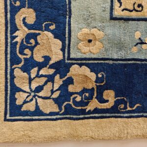 High pile rug corner detail showing tan floral designs on navy and light blue fields.