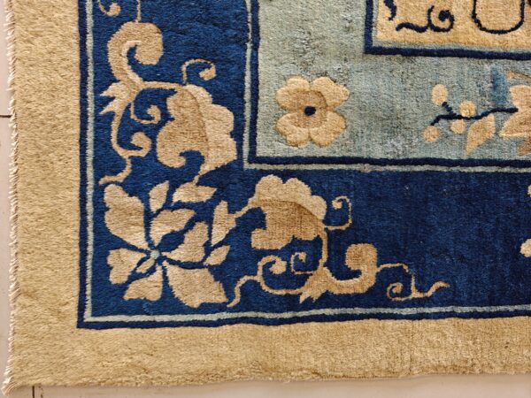 High pile rug corner detail showing tan floral designs on navy and light blue fields.