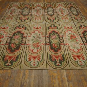 Repeating panel rug with floral bouquets in cream, red, and olive green on distressed wood flooring.