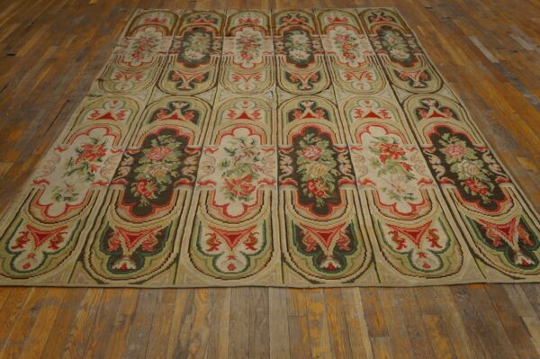 Repeating panel rug with floral bouquets in cream, red, and olive green on distressed wood flooring.